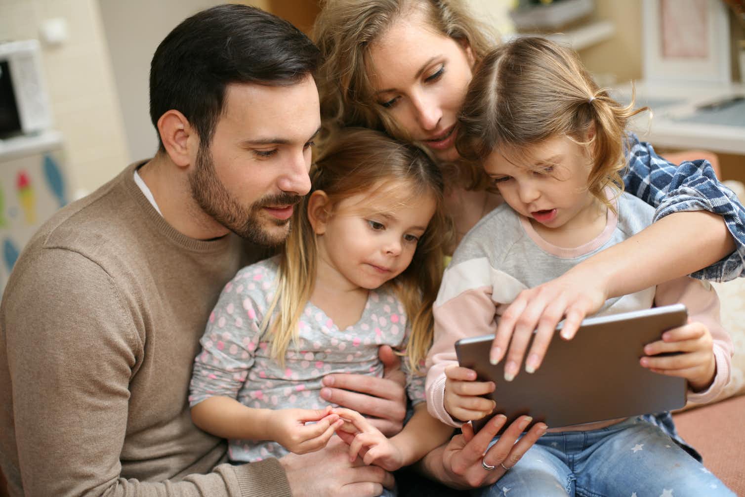 Family of a mother, father and two daughters, using a tablet