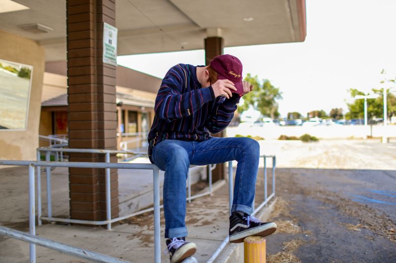 Young person sitting on rail next to building