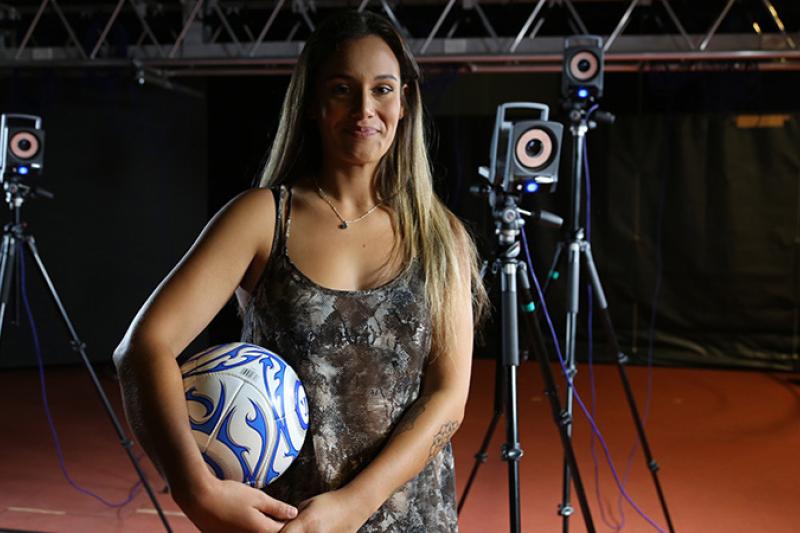 female teaching student posing with a volleyball in hand