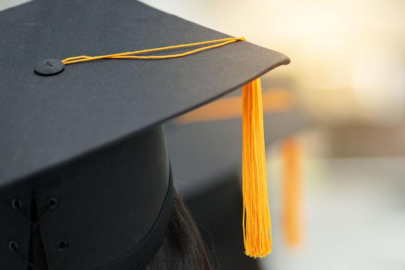 Close up of university graduation cap with yellow tassle.