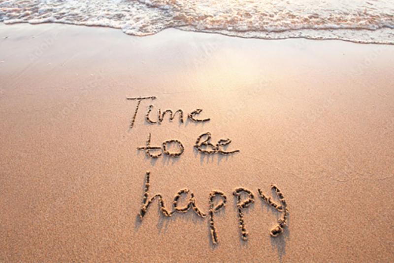 A beach with the words 'Time to be happy' written into the sand.