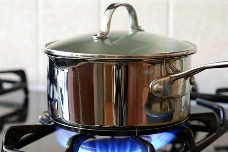 A saucepan sits over an open flame on a gas stove.