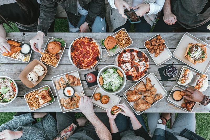 Birds-eye view of a group of people sit around a table, sharing food.