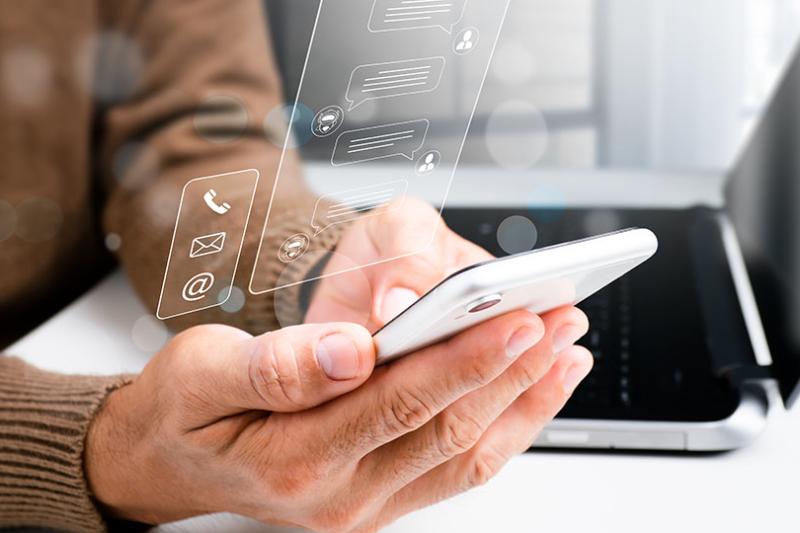 A person holds a phone, using generative AI, while sitting in front of a laptop.