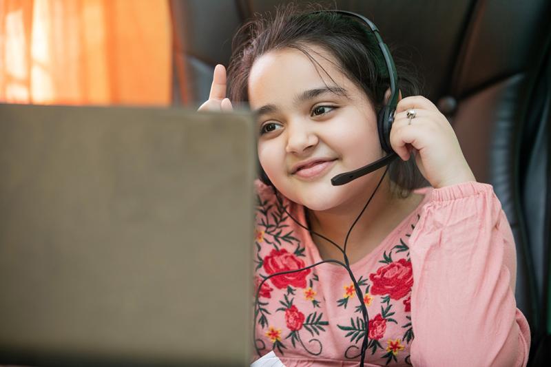 Young girl with a headset on learning remotely