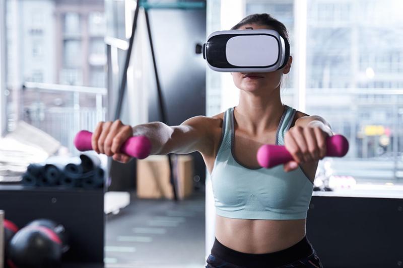 A woman exercising at the gym wearing a VR headset.