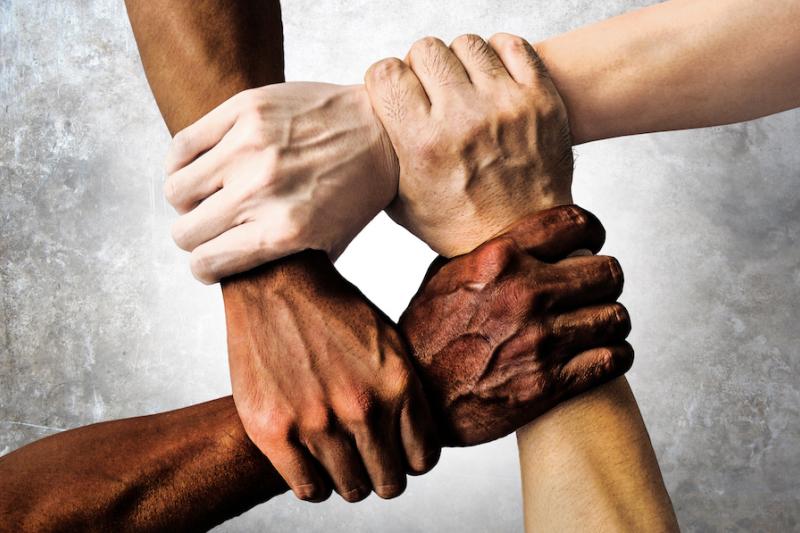 Hands of different colours gripping wrists