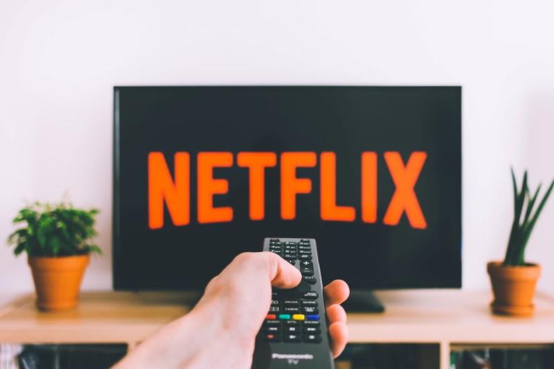 Person's hand with remote control watching Netflix on TV