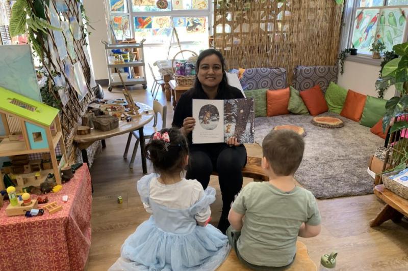 Pearl Jain is reading a book to two children in a childcare centre.