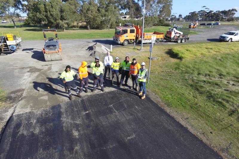 Workers and researchers standing on road made of recycled demolition waste.