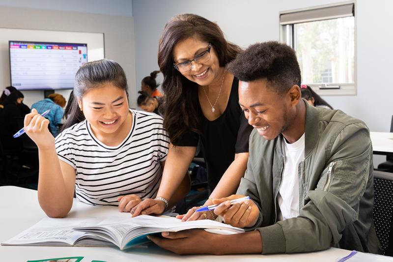 A teacher in a classroom helping out students.