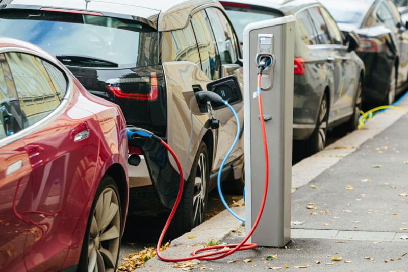 Photo of parked electric vehicles being charged at an EV charging station