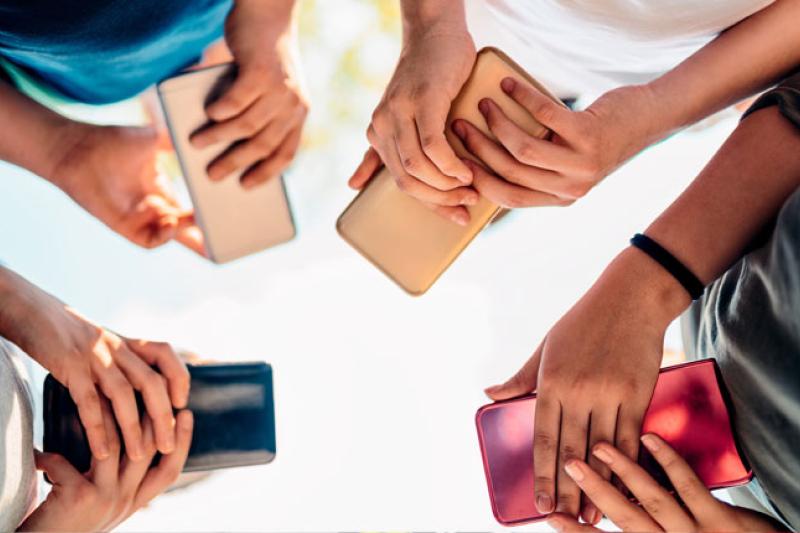 abstract photo looking up at hands of four teenagers holding smartphones