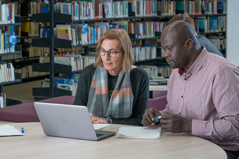 Two people in VU Library on laptop