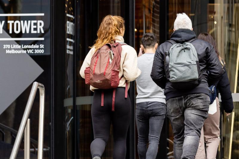 A group of students walking into a building. A sticker on the building says "City Tower"