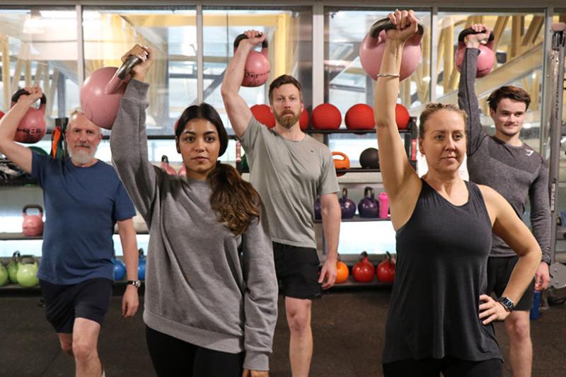 Gym goers holding up kettlebells during a training session at Footscray Park Campus gym.