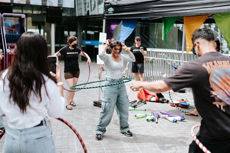 A group of young people hoola-hooping in a university courtyard