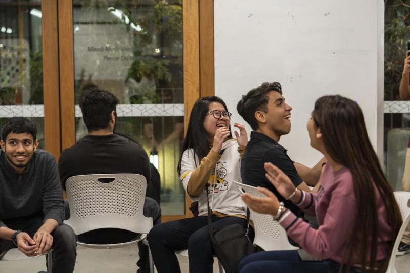 A multicultural group of young people laugh while enjoying a conversation