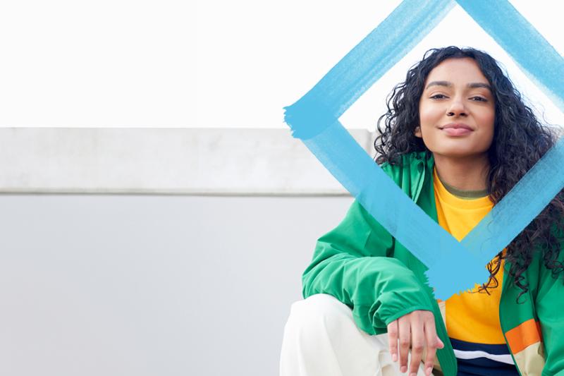 A relaxed young woman smiles for the camera, with a blue diamond logo superimposed