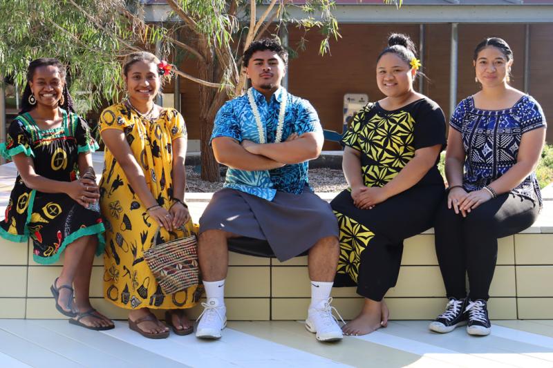 Five students sitting outside smiling at the camera