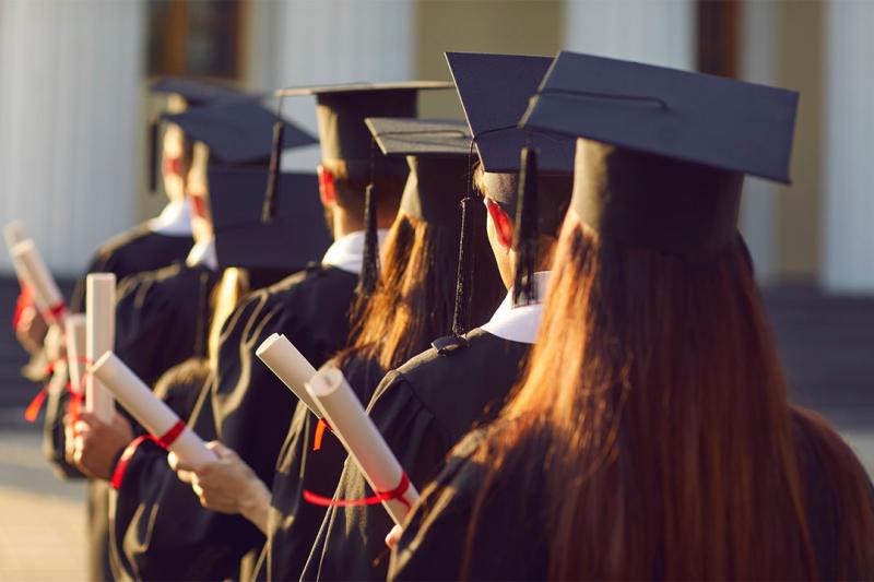 Students in graduation robes, holding scrolls.