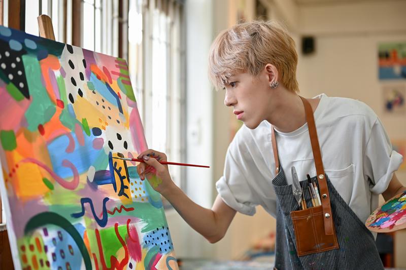 A young person paints a colourful artwork