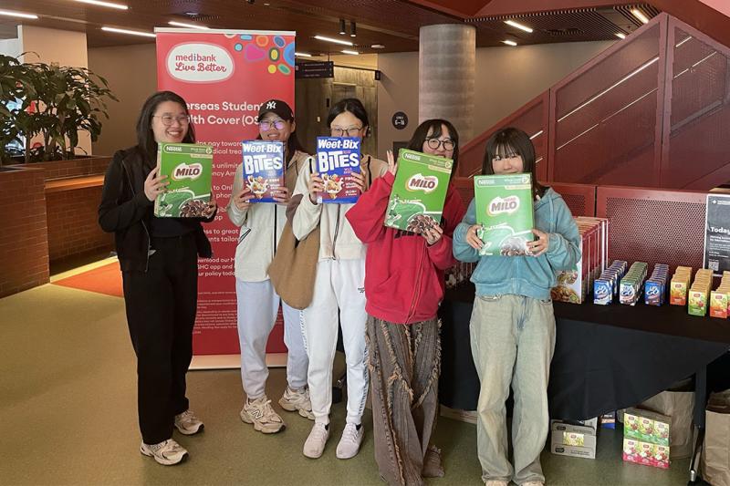 Five students stand holding breakfast cereals in VU's City Tower campus.