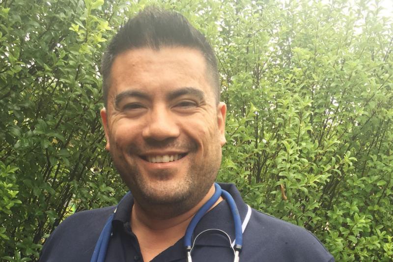 Shane Bautista standing outside with a stethoscope around their neck.