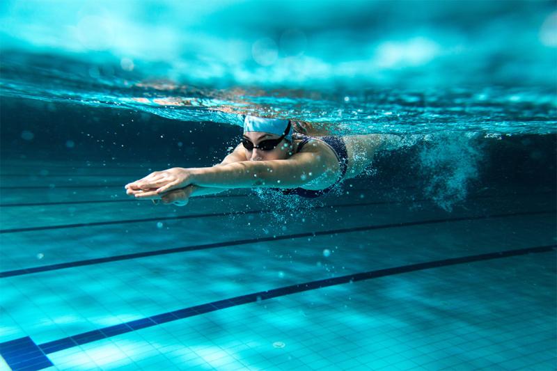 Female swimmer at the swimming pool. Underwater photo.