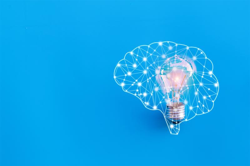 Image of the neural pathways of a brain with a lightbulb inside it, against a blue background.