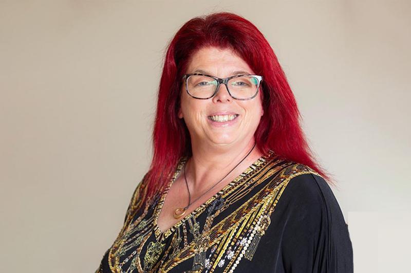 An older woman with red hair poses for a poses for a professional portrait