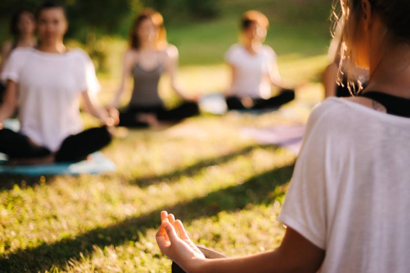 A group of people doing meditative yoga outdoors.