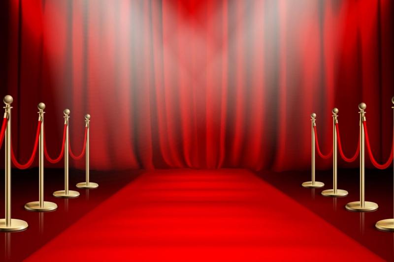 A red carpet surrounded by bright lights leading to a red curtain.