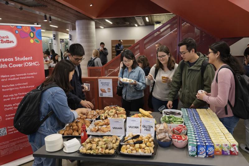 A group of students around a table full of hot and cold breakfast snack