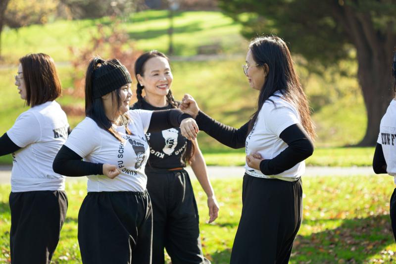 A group of martial art students practicing in a park with their teacher watching.