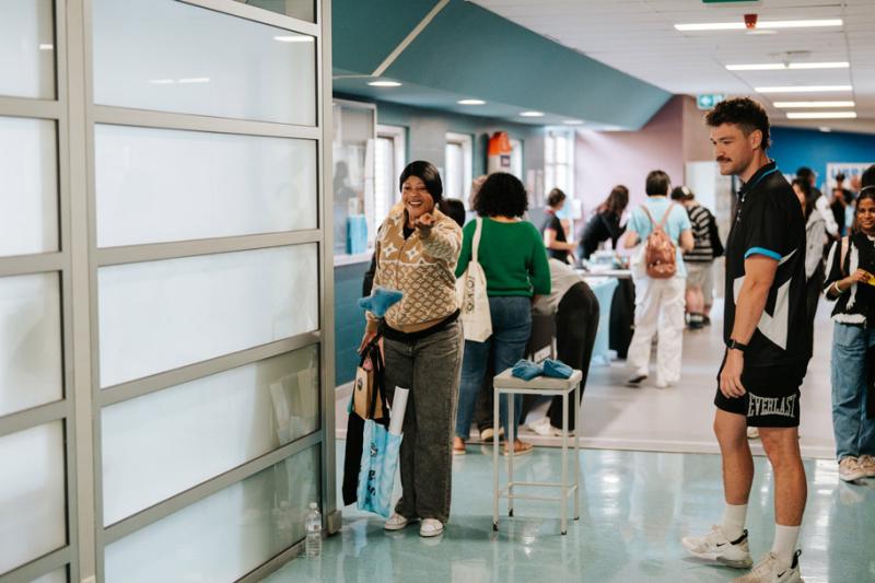 Students browse stalls in a bright, white hallway