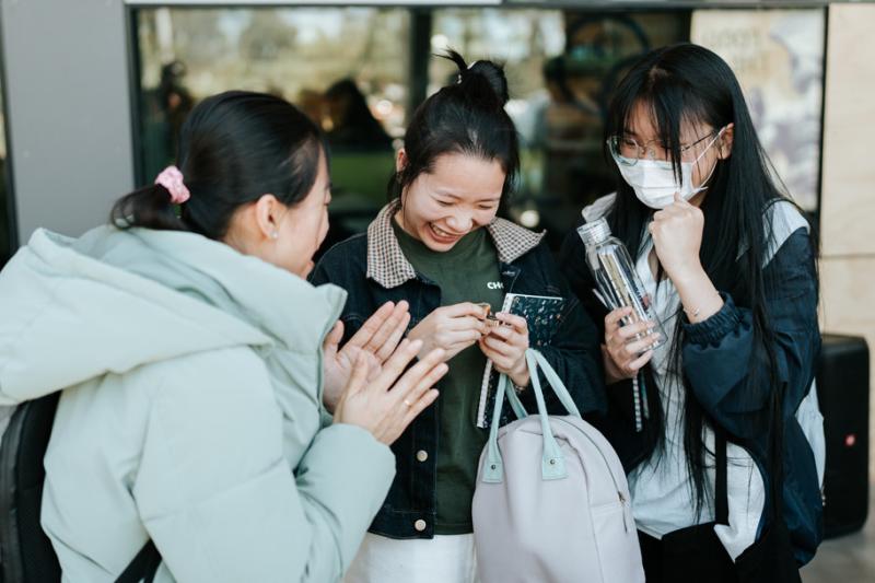 3 young women laughing and enjoying themselves outside a sleek glass building entrance