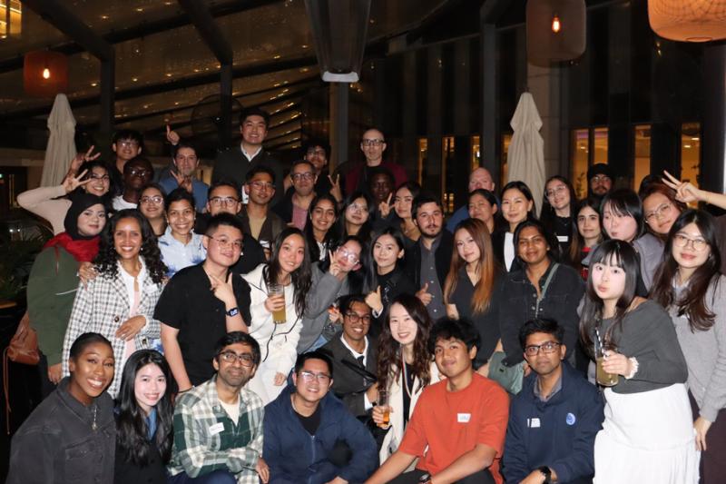 Large group of smiling people at evening networking event in casual setting.