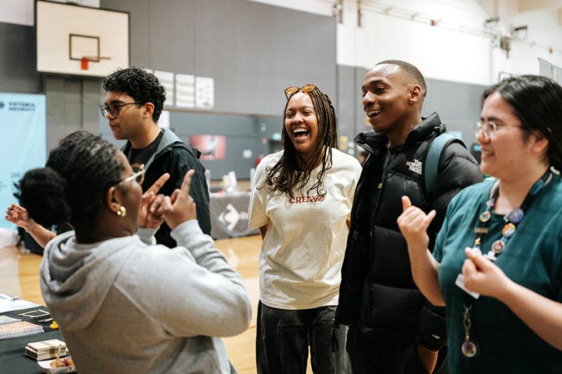 A group of happy, relaxed students at a casual event in a large indoor baskeball courts