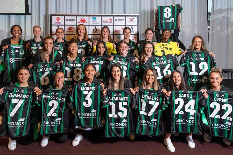 Women's football team proudly hold up team jerseys