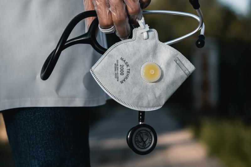 A gloved hand holding a mask and stethoscope