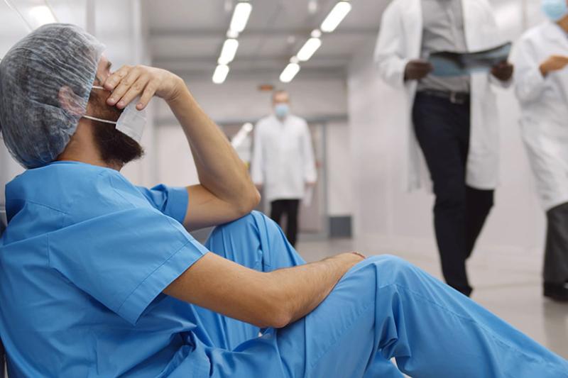 Healthcare workout experiencing burnout in a hospital corridor.