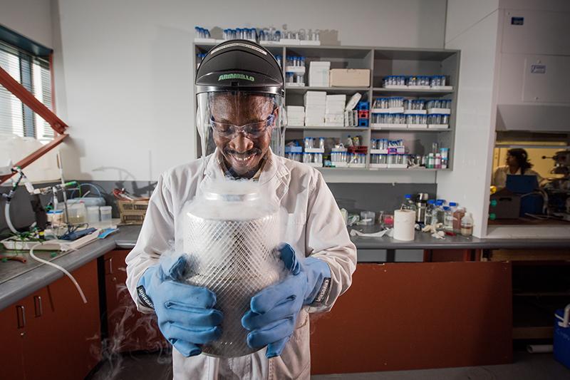 A person smiling while working in a research labratory.
