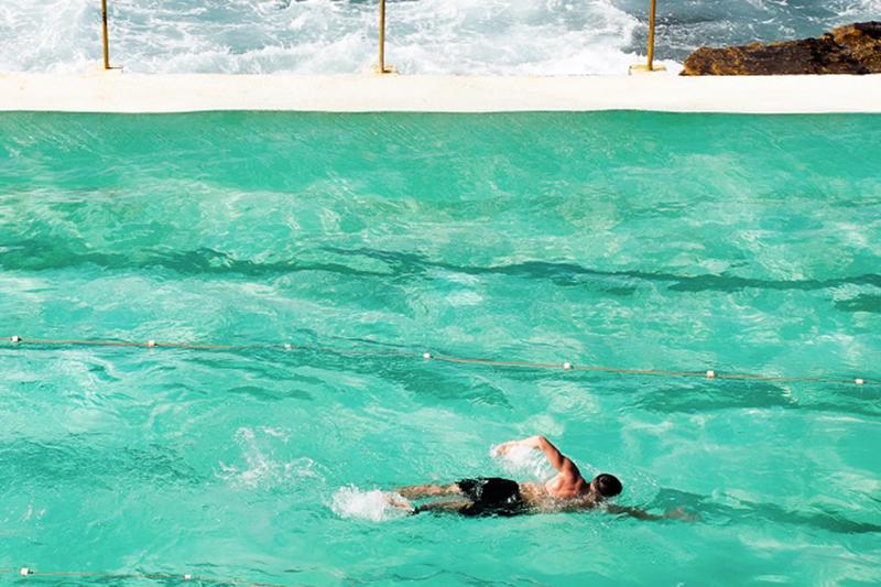 Man swims in a pool near the ocean