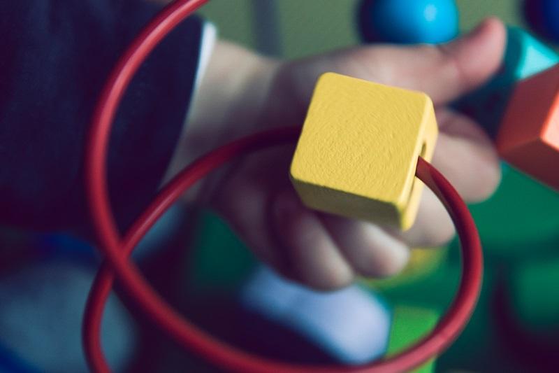 Toddler hand playing with bright wooden toy