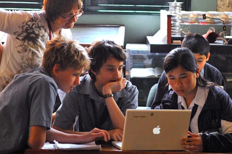 School students and teacher looking at a computer screen