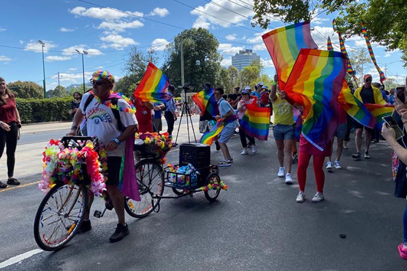 A group on bikes and on foot waving rainbow flags