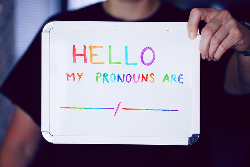 Person holding sign that reads 'Hello, my pronouns are...' (photo by Sharon McCutcheon on Unsplash)