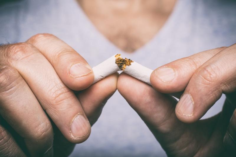  man breaking a cigarette in two.