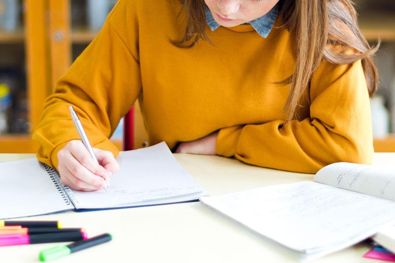  A year 7 student student in a yellow jumper does homework.